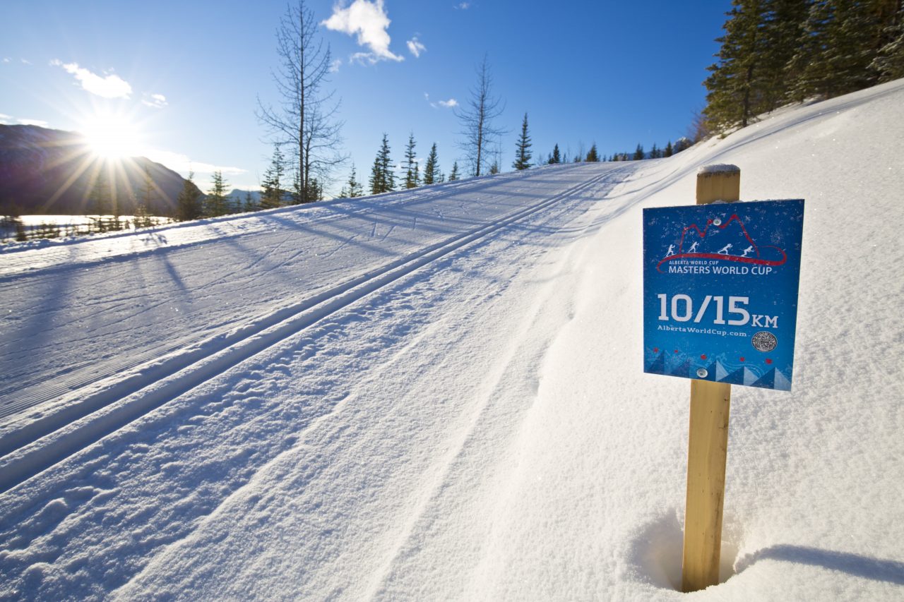 Freshly groomed classic tracks in low sun beside a Masters World Cup course marker
