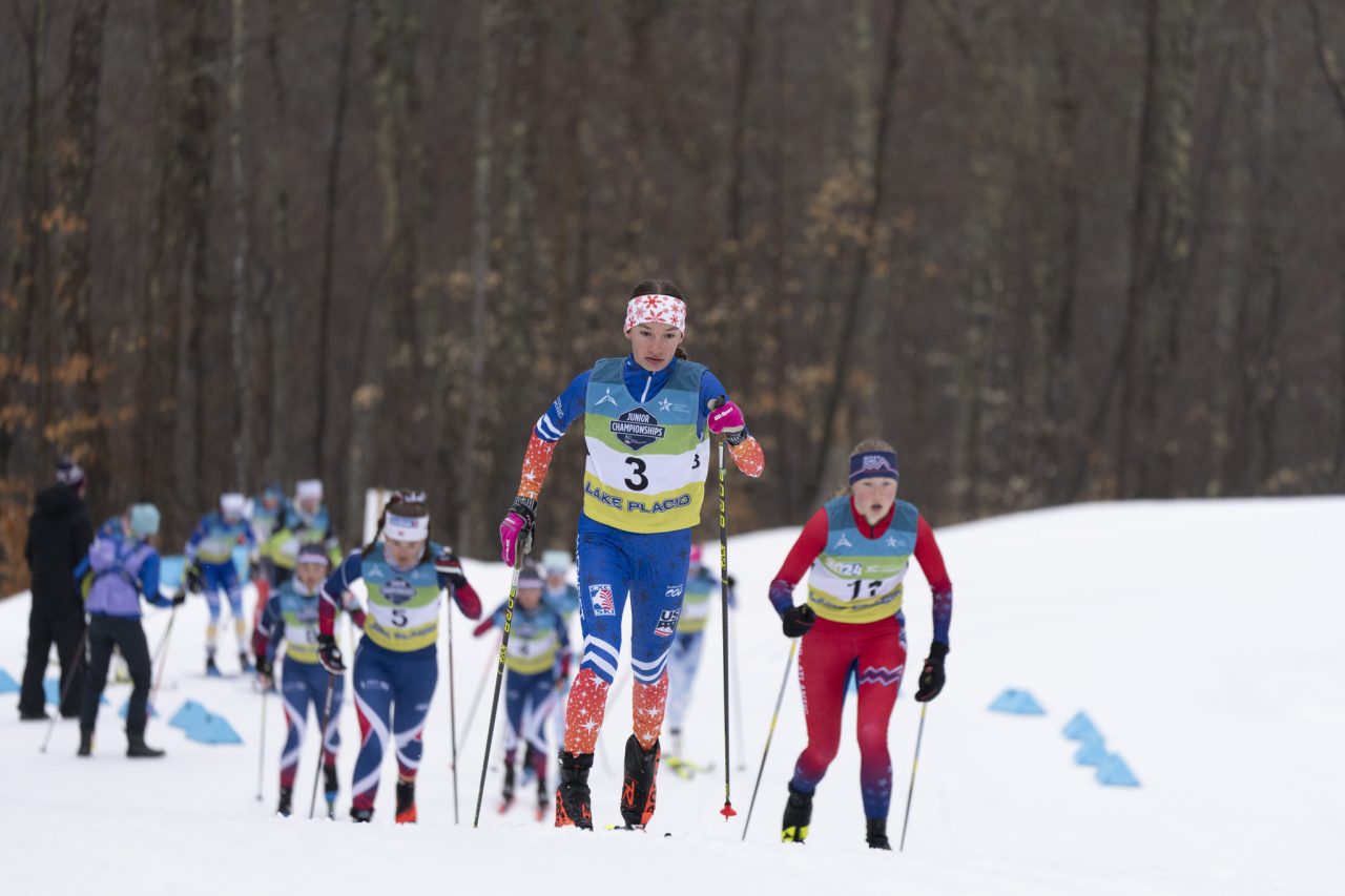 Linnea Ousdigian in bib 3 leads a pack of junior skiers uphill in a classic race