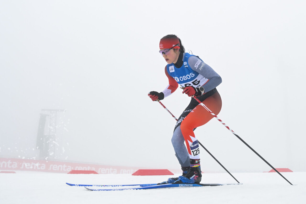 Alison Mackie skiing in a Canadian race suit through fog at Holmenkollen.