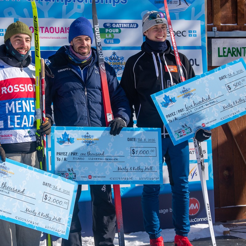 Three skiers holding oversized presentation cheques for two thousand, one thousand and five hundred dollars.