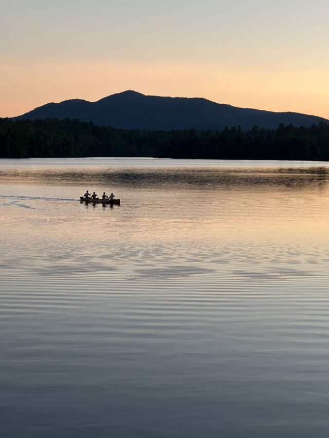 A canoe with several paddlers silhouette